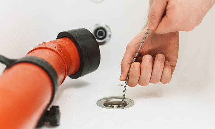 Plumber Cleaning Sink Using Wire